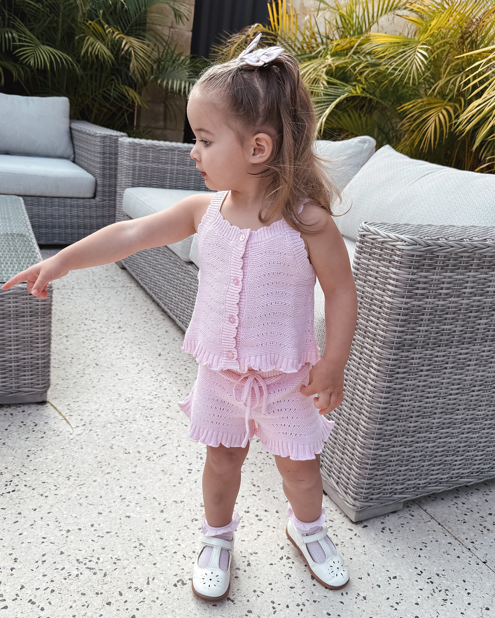 Young girl in a florence lace pink knitted top and shorts standing outdoors on a patio