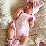 our pretty pink hello world has scalloped edges on short sleeve for arms and delicate knitted frill on legs. At the crotch and down the centre and on shoulder we have added pink resin flower buttons. Matches with our bonnet booties beanie and other pretty pink items. Hello world type in the centre is white surrounded by delicate flowers. The type is in running writing with capital letters at the start - beautiful for baby girl