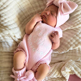 our pretty pink hello world has scalloped edges on short sleeve for arms and delicate knitted frill on legs. At the crotch and down the centre and on shoulder we have added pink resin flower buttons. Matches with our bonnet booties beanie and other pretty pink items. Hello world type in the centre is white surrounded by delicate flowers. The type is in running writing with capital letters at the start - beautiful for baby girl