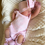 our pretty pink hello world has scalloped edges on short sleeve for arms and delicate knitted frill on legs. At the crotch and down the centre and on shoulder we have added pink resin flower buttons. Matches with our bonnet booties beanie and other pretty pink items. Hello world type in the centre is white surrounded by delicate flowers. The type is in running writing with capital letters at the start - beautiful for baby girl