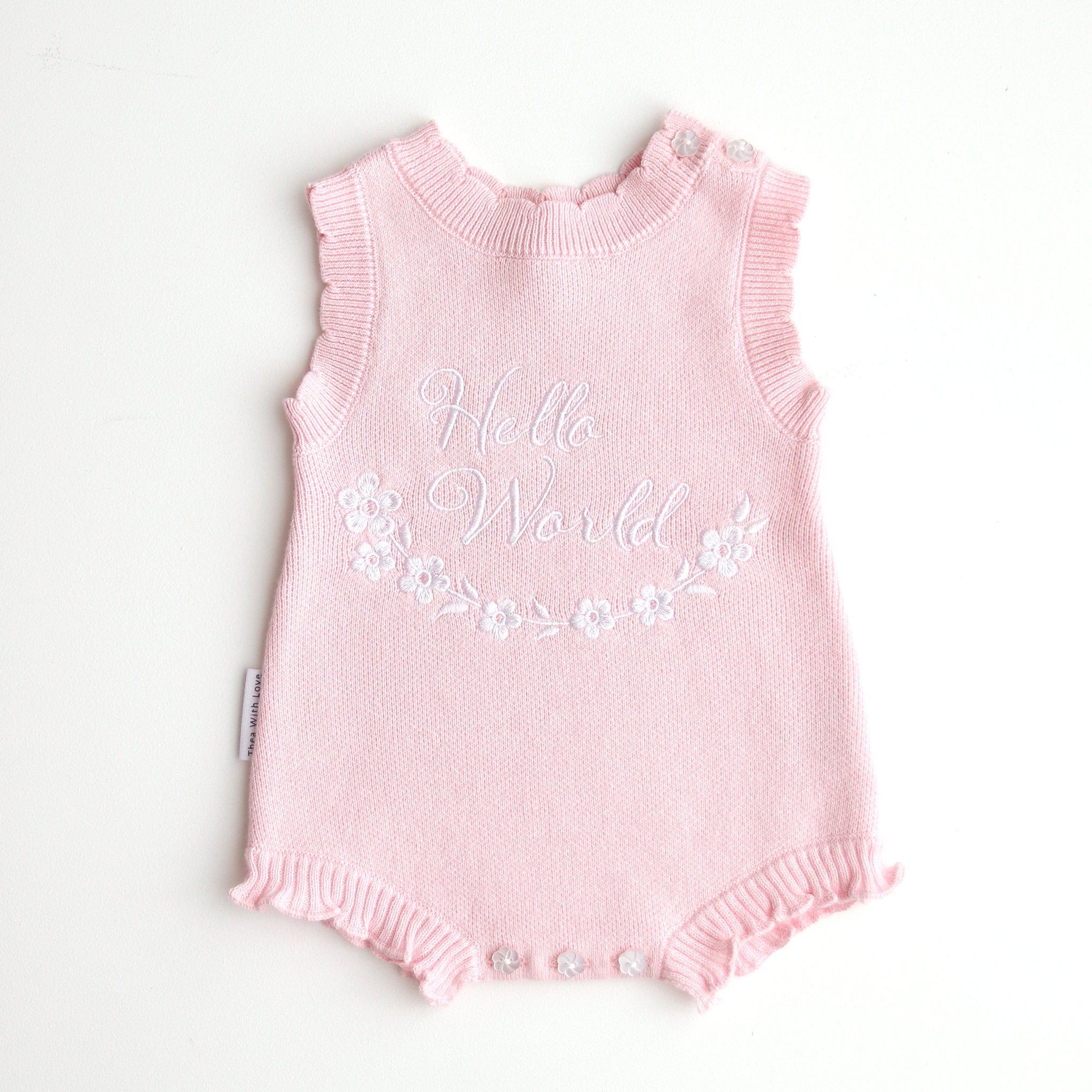 our pretty pink hello world has scalloped edges on short sleeve for arms and delicate knitted frill on legs. At the crotch and down the centre and on shoulder we have added white resin flower buttons. Matches with our bonnet booties beanie and other pretty pink items. Hello world type in the centre is white surrounded by delicate flowers. The type is in running writing with capital letters at the start - beautiful for baby girl
