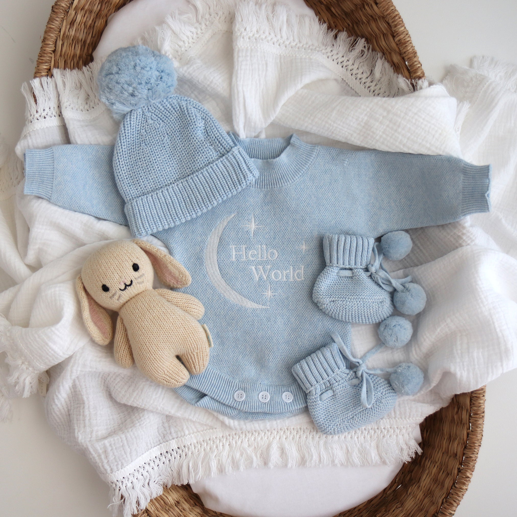 Sky Blue Hello World announcement romper with matching beanie and booties on white fringe muslin swaddle
