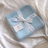 Baby blue cotton knit blanket with stars and moon pattern by Thea With Love, folded neatly on white background.