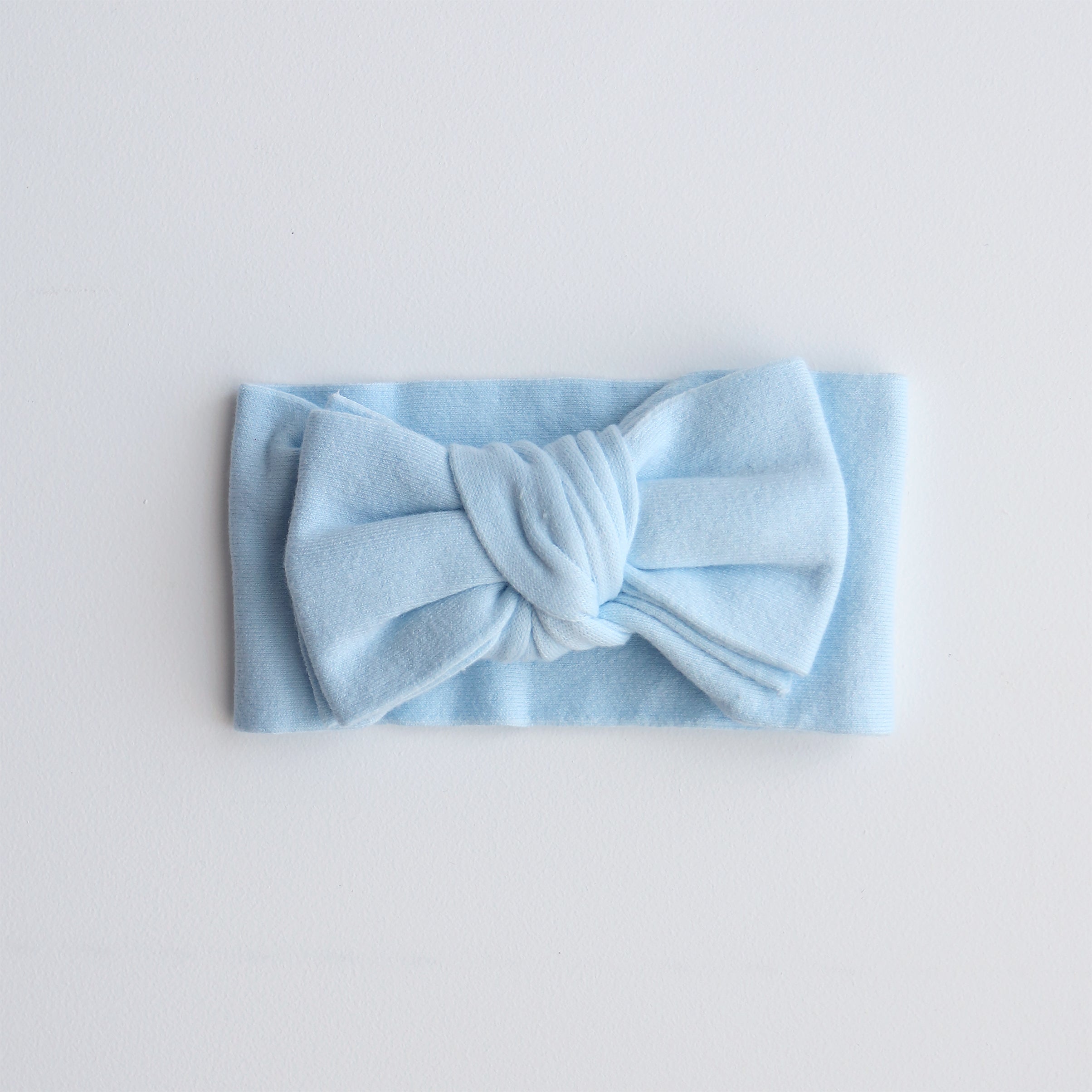 Light blue headband with a bow on a light gray background