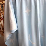 Light blue curtain with star and moon patterns draped over a cane bassinet.