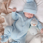 baby wearing chunky knit romper with matching beanie and pom pom booties