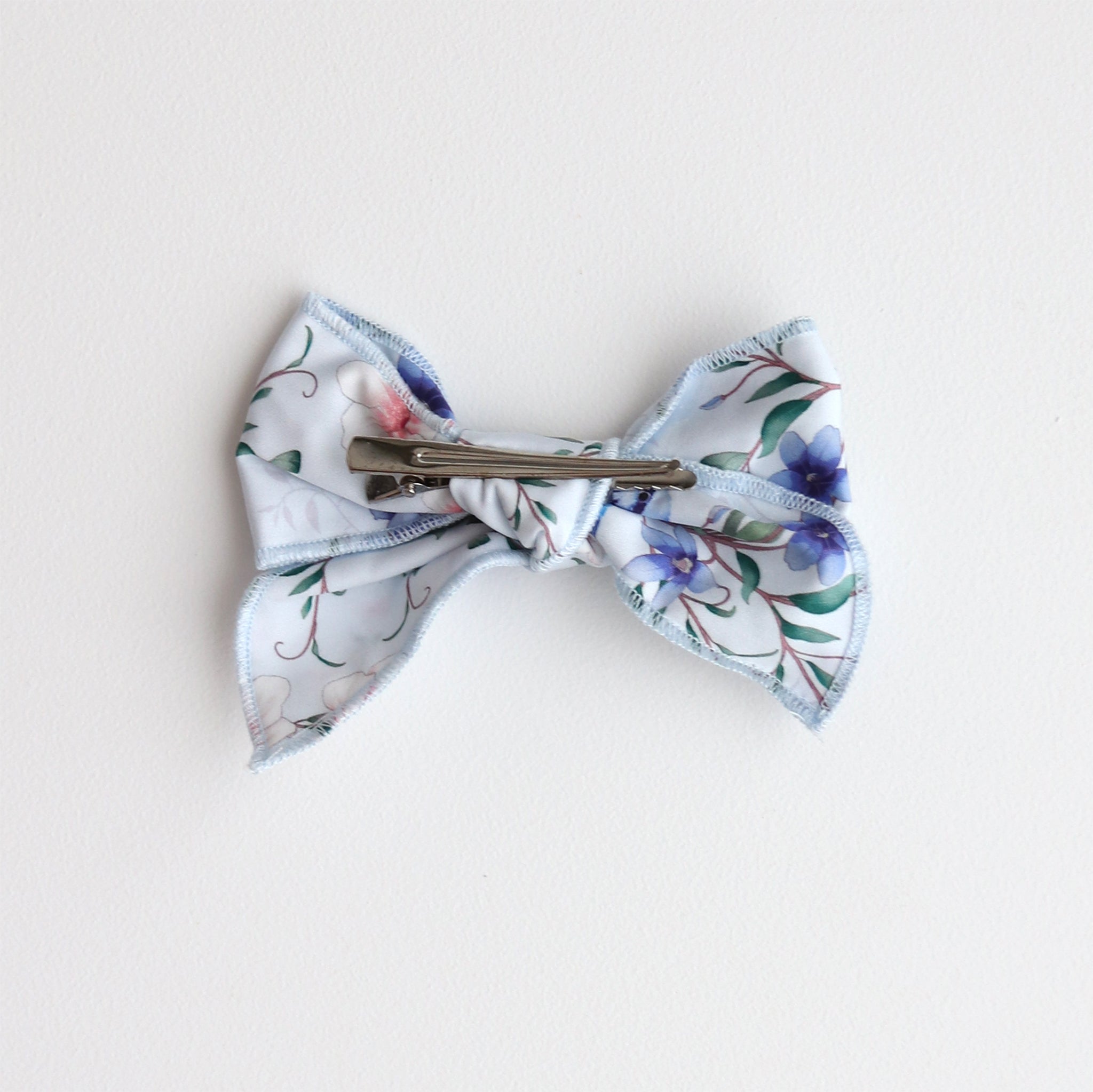 Floral patterned bow with a clip on a light background