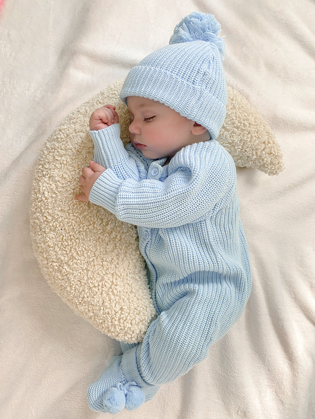 baby wearing chunky knit romper with matching beanie and pom pom booties