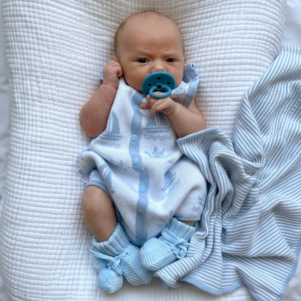 newborn baby wearing the coastal bubble one piece romper with snap buttons down the front laying on a blanket