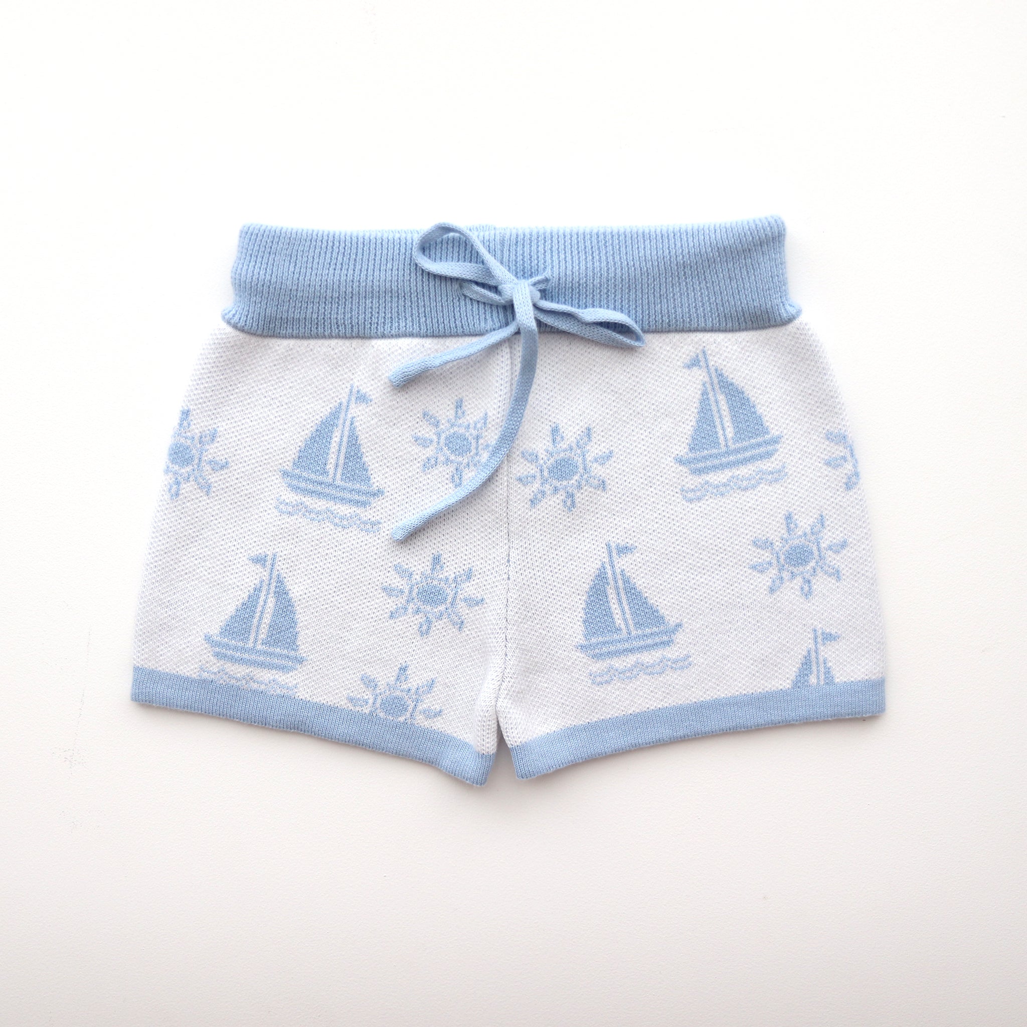 cotton knitted shorts with blue boat pattern on white background. Blue trims and blue elastic waist with drawstring. Waist band is 4 cm high and the leg trim is 1.5 cm high
