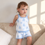 Toddler wearing Coastal Cotton Knitted Shorts and Singlet Top, light blue and white knit with sailboat and sun pattern, sitting on a beige sofa