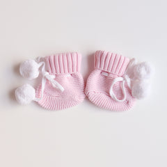 cute pom pom booties - booties are pink with warm white pom pom and warm white lace tied in bow to secure booties