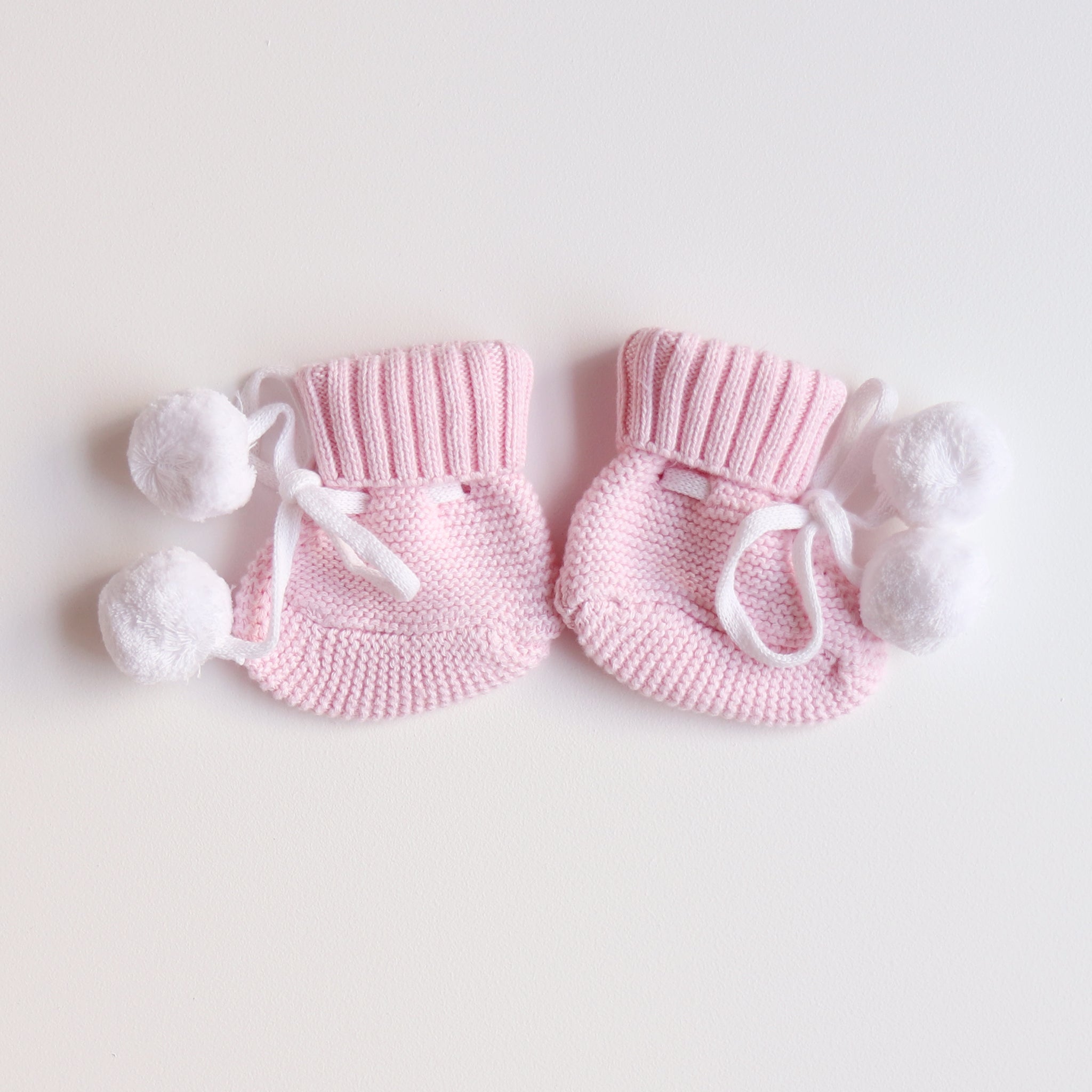 cute pom pom booties - booties are pink with warm white pom pom and warm white lace tied in bow to secure booties