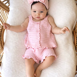 Baby in pink florence lace top and shorts with a matching bow headband lying in bassinet