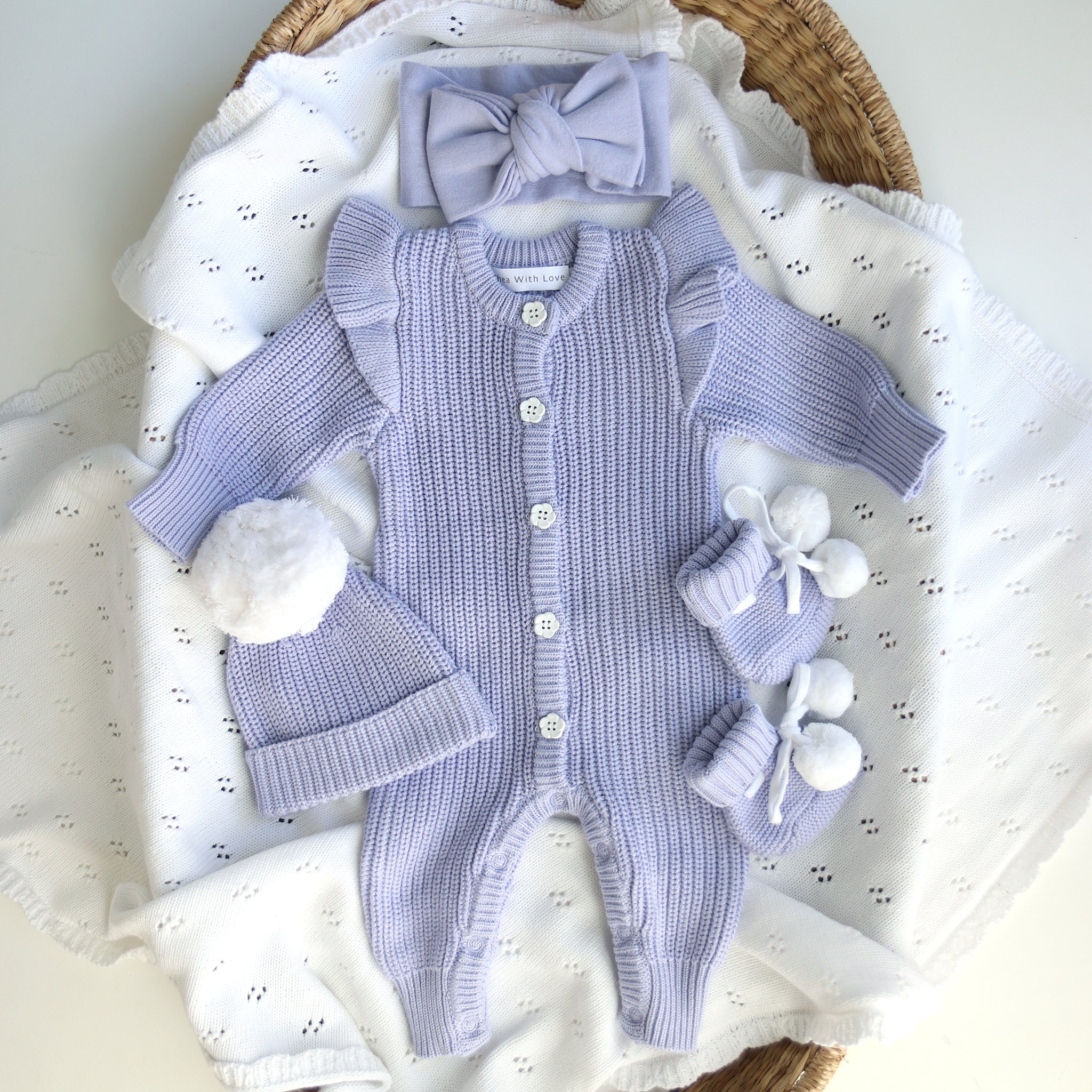 frilly romper flatlay with beanie, bow and booties