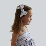 Young girl wearing a floral dress and headband against a plain background

Details