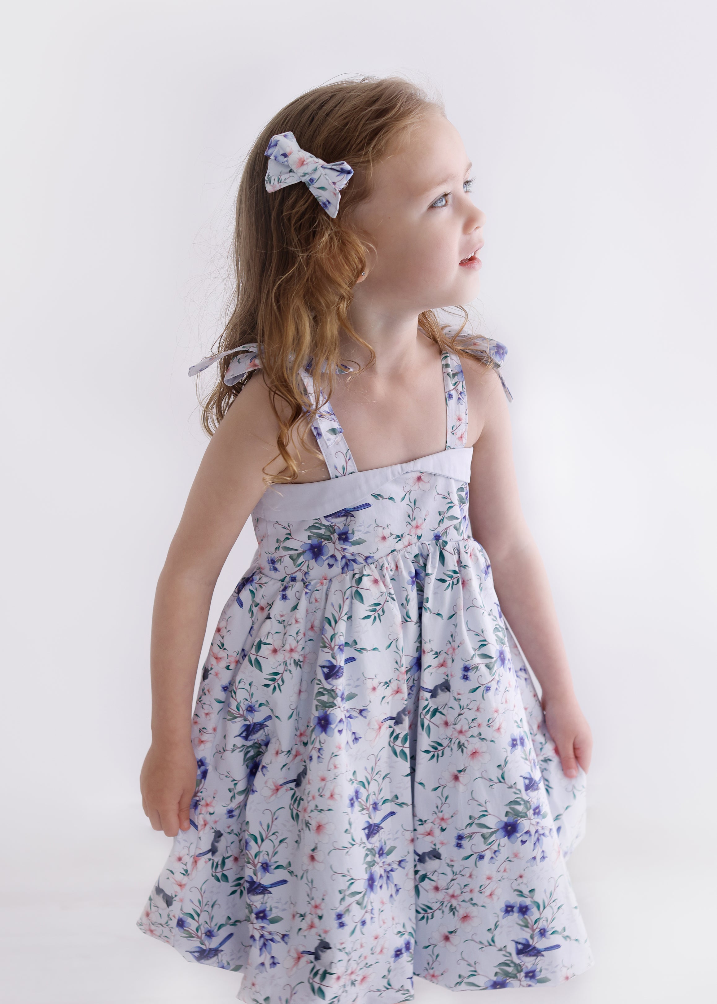 Young girl wearing a floral dress against a plain background
