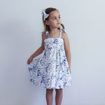 Young girl wearing a floral dress against a plain background