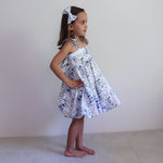 Young girl wearing a floral dress against a plain background