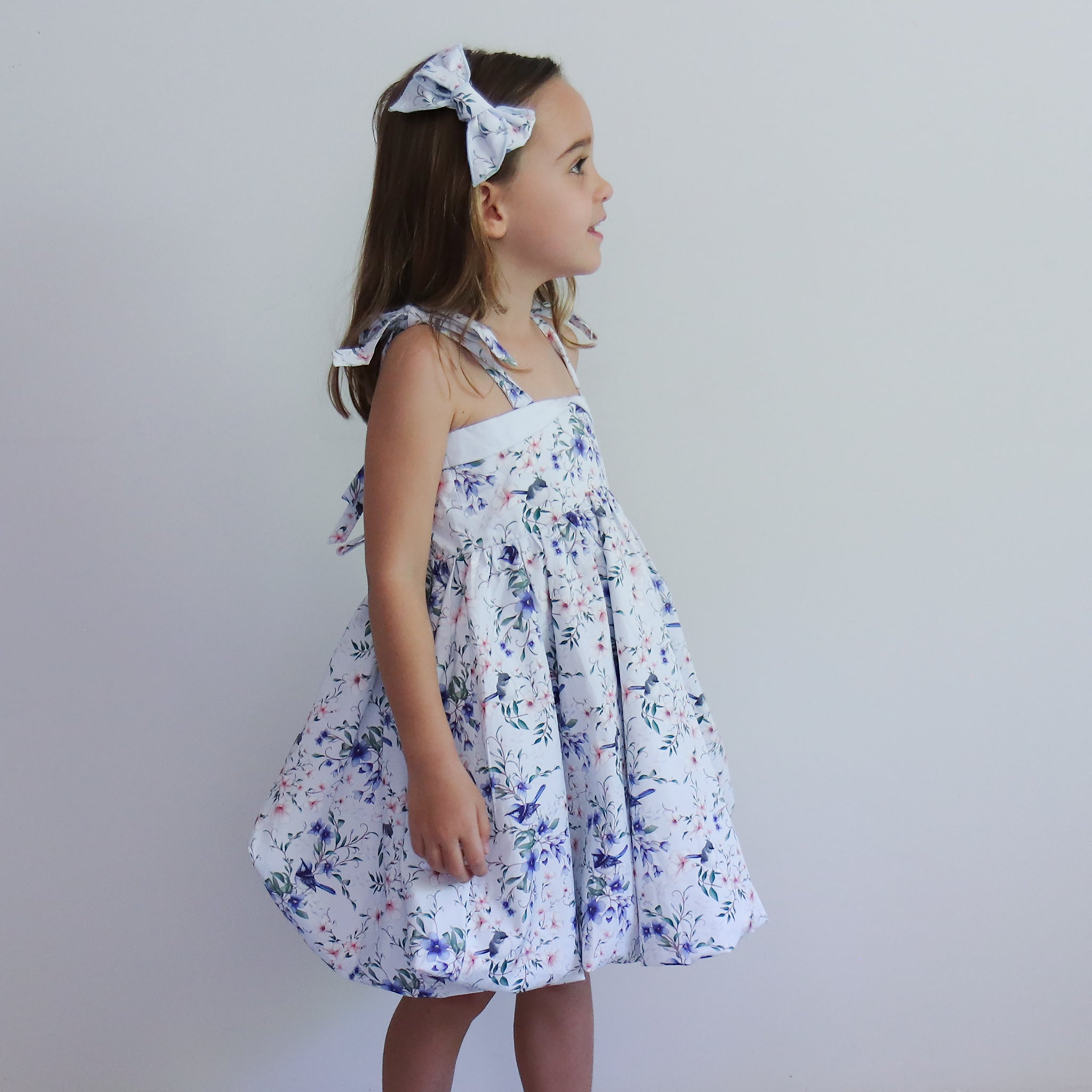 Young girl wearing a floral dress against a plain background