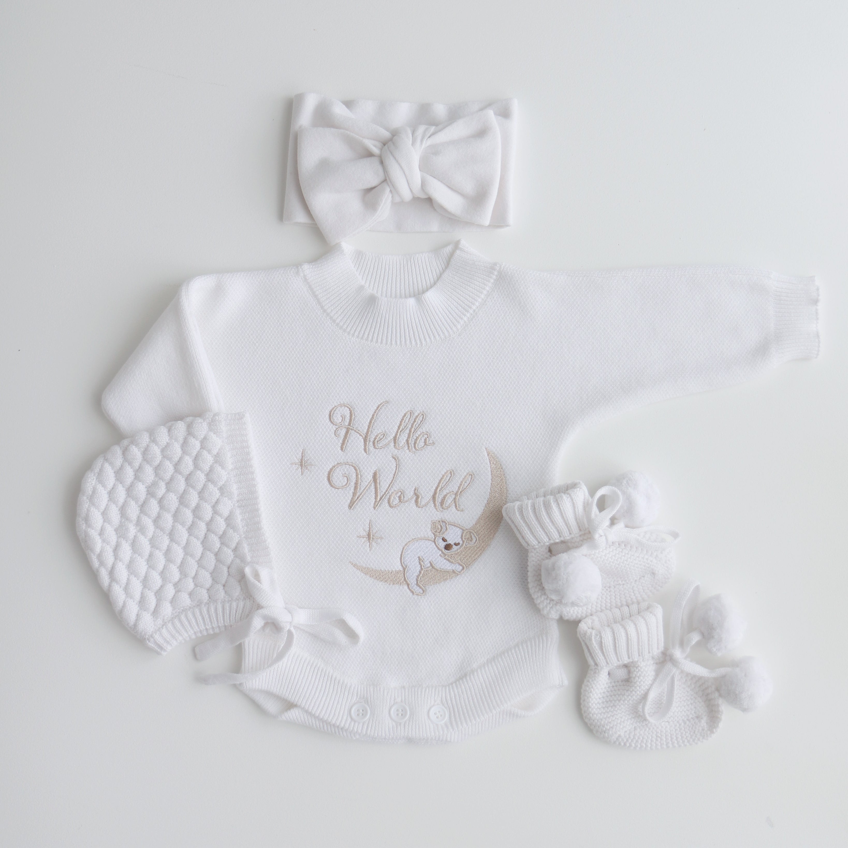Koala hello world romper flatlay with matching warm white jacquard knit bow bonnet and booties - perfect for newborn gift
