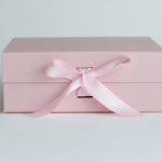 Pink gift box with a pink satin ribbon on a light grey background