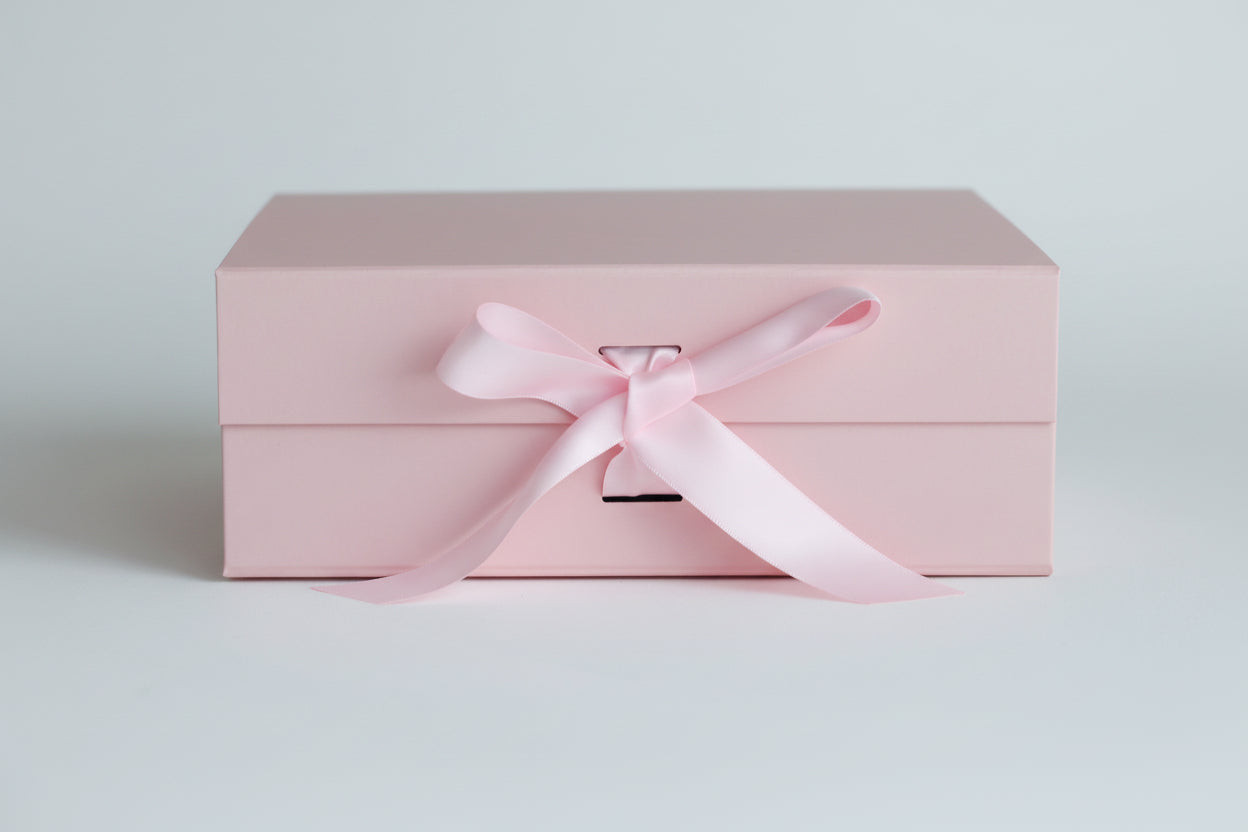 Pink gift box with a pink satin ribbon on a light grey background