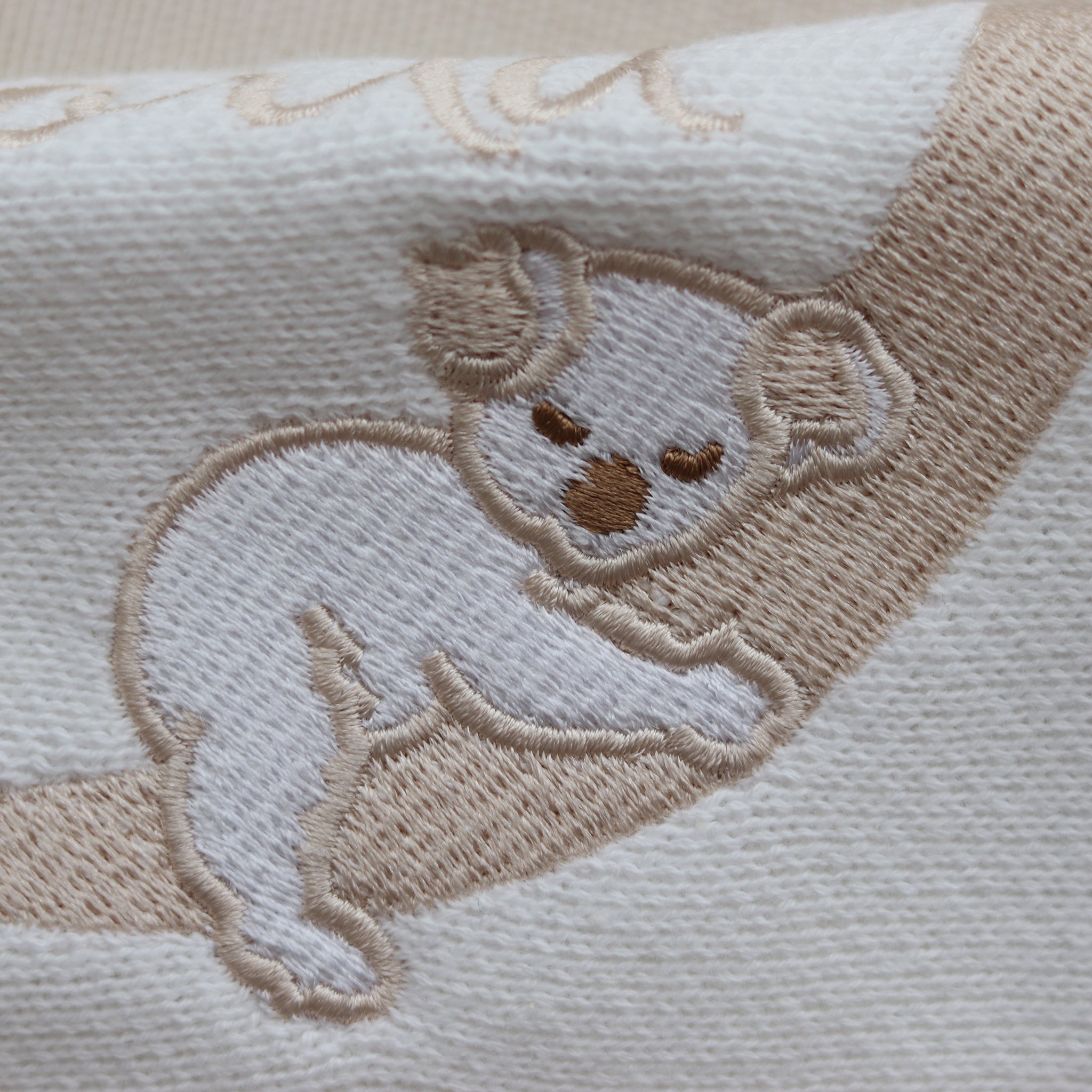 Flatlay of the Hello World Koala romper showing the embroidery imperfection — the koala’s face appears untidy with a slightly larger nose.