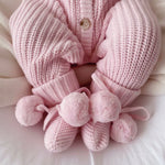 baby wearing pink booties with pom poms