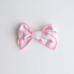 Pink and white bow on a light gray background