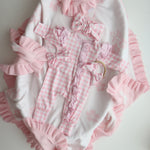 Pink and white checkered baby outfit with ruffles on a light background