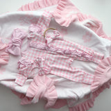 Pink and white baby outfit with ruffles and checkered patterns on a white background