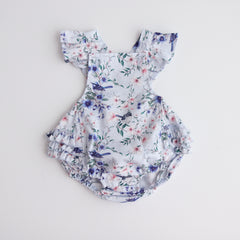 playsuit with frill on shoulders,crossover straps, frill on the lower bottom and snaps  at crotch for easy changing. Flatlay showing the playsuiton white back ground