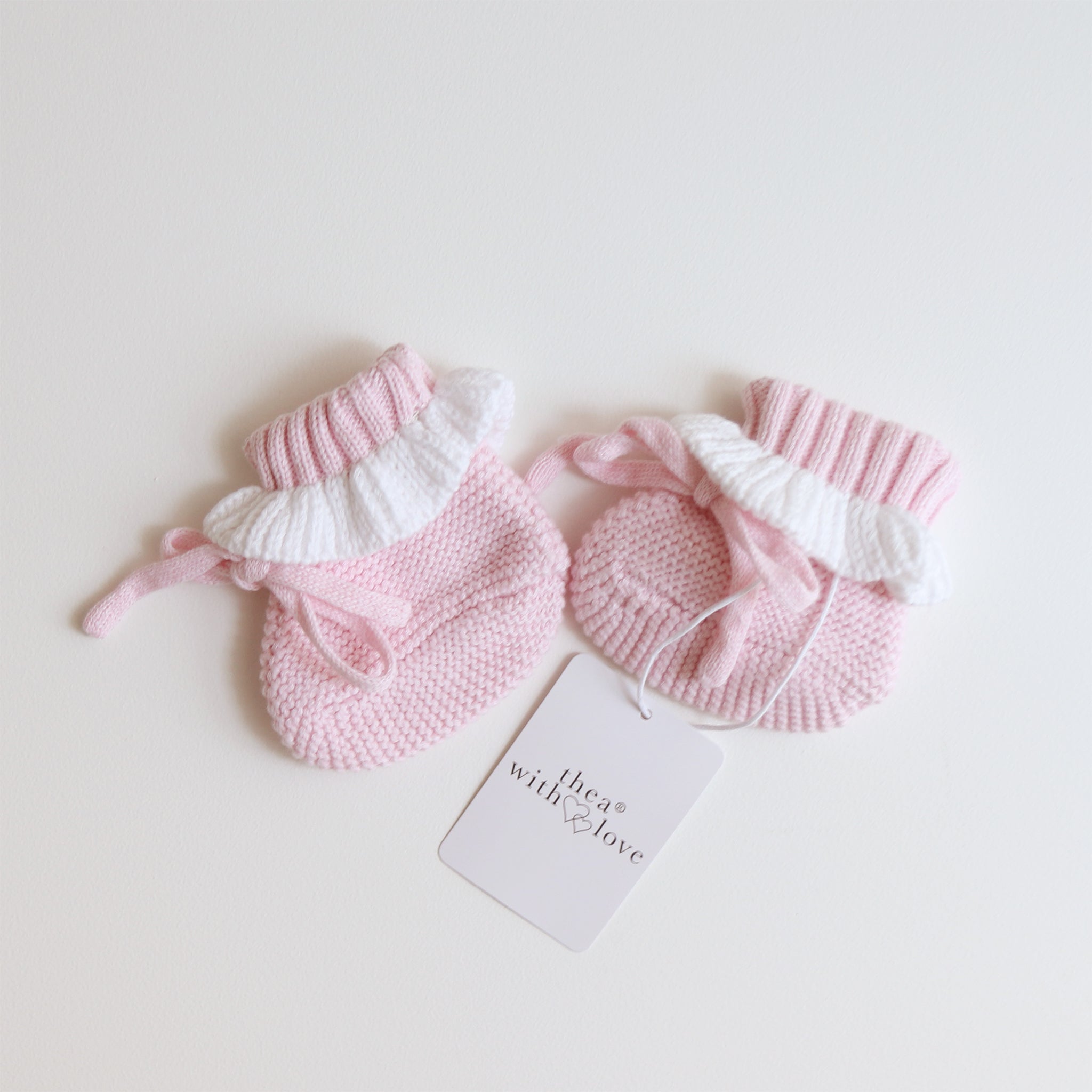 pink knitted booties with warm white frill  at the top of booties. pink bootie lace which can be tied into a bow to secure booties on to baby's foot