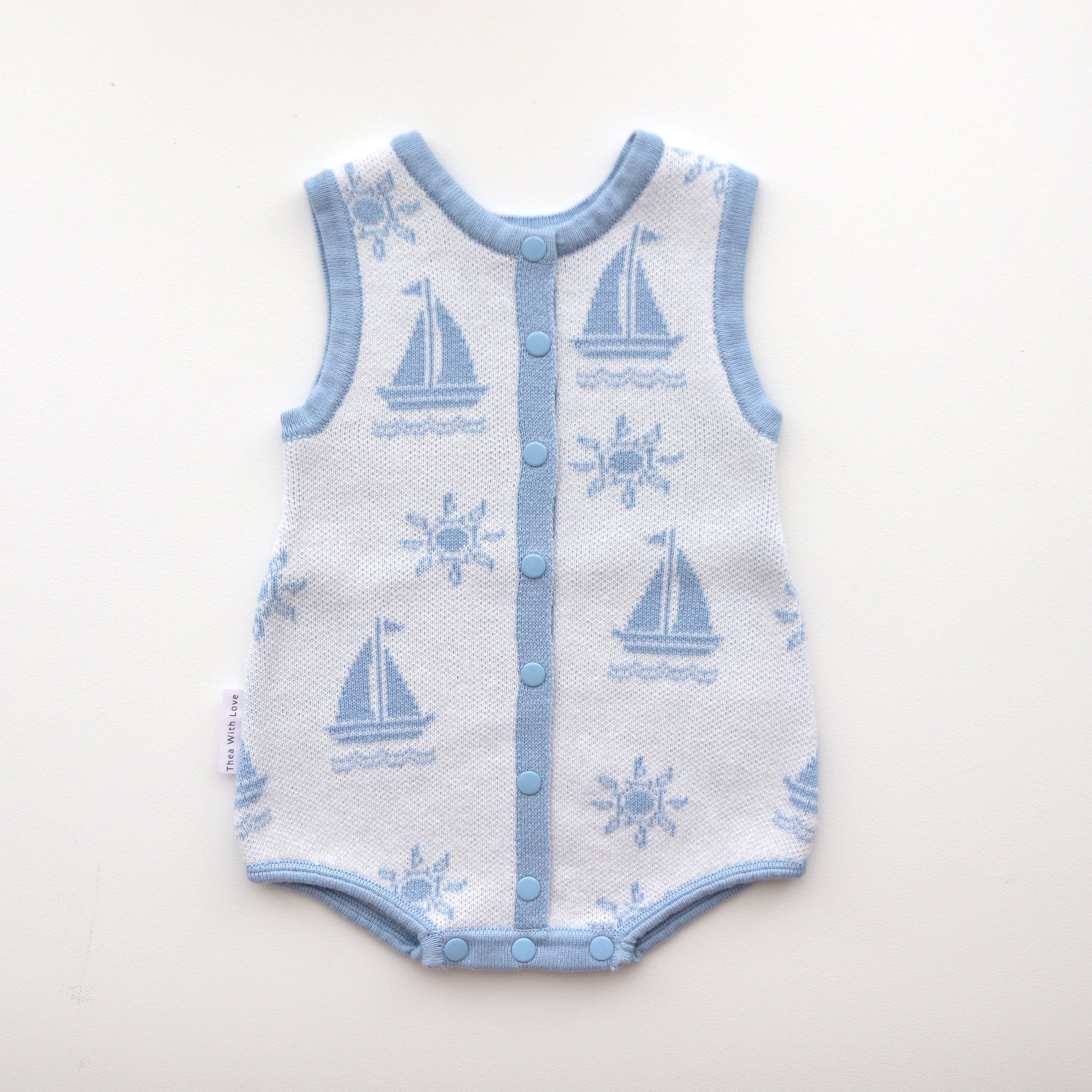 blue trim leg neck sleeves and centre trim also blue with blue snap buttons and snap buttons on crotch, sun and boat pattern on white background