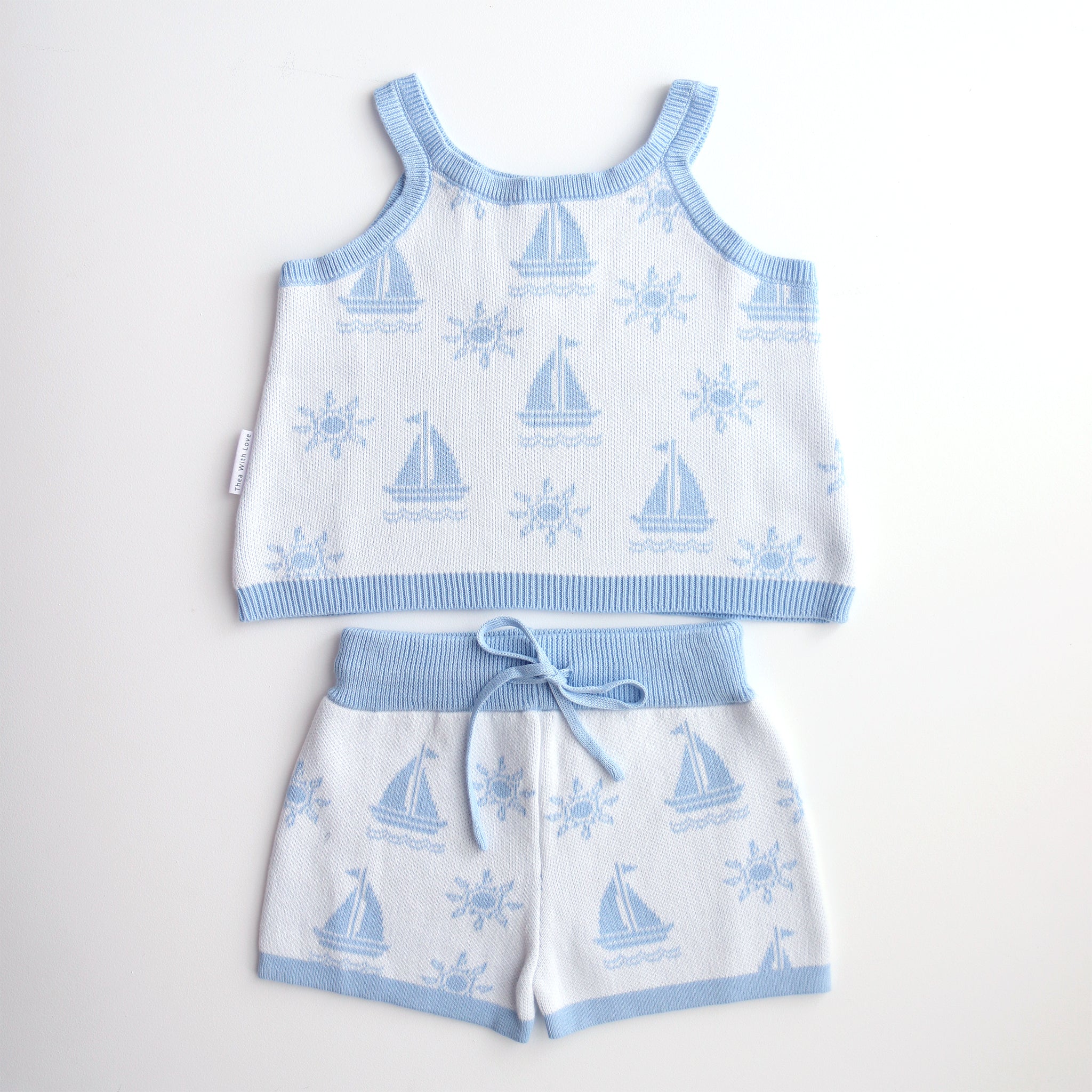 cotton knitted shorts with blue boat pattern on white background. Blue trims and blue elastic waist with drawstring. Waist band is 4 cm high and the leg trim is 1.5 cm high
