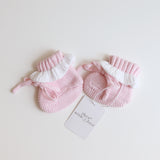 pink knitted booties with warm white frill  at the top of booties. pink bootie lace which can be tied into a bow to secure booties on to baby's foot