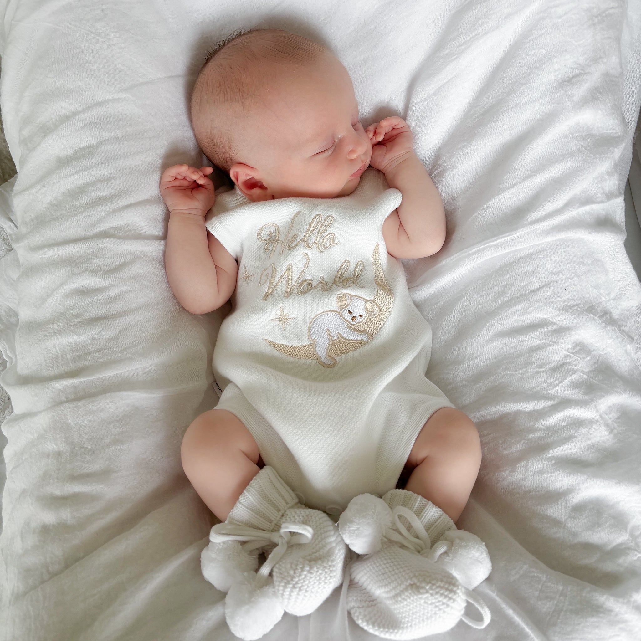 Our koala hello world summer features a baby koala sleeping on eclipse shape  moon. 2 stars are also added. The embroidery is running writing. The embroidery yarn is glossy so the hello world shines in the sunlight. Romper is white knitted fabric. short sleeves and legs for summer. 