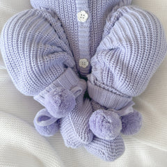 Set of purple knitted baby booties with pom pom on a white background