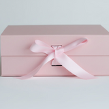 Pink gift box with a satin ribbon on a light gray background