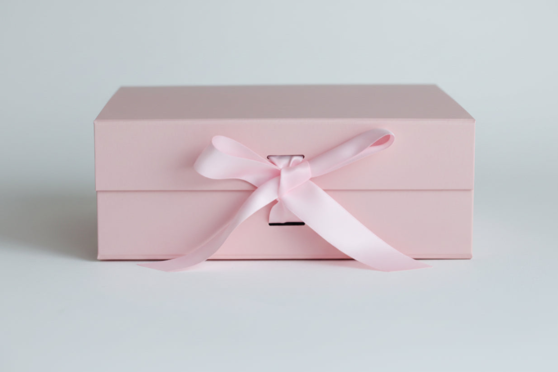 Pink gift box with a satin ribbon on a light gray background