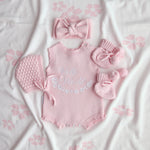 our pretty pink hello world has scalloped edges on short sleeve for arms and delicate knitted frill on legs. At the crotch and down the centre and on shoulder we have added pink resin flower buttons. Matches with our bonnet booties beanie and other pretty pink items. Hello world type in the centre is white surrounded by delicate flowers. The type is in running writing with capital letters at the start - beautiful for baby girl 